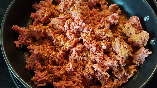 Ground beef in skillet with seasoning